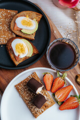 The concept of a healthy homemade breakfast with fresh strawberries, avocado toast and fish, sweet curds with chocolate, chicory in a cup. Vegetarian menu in the restaurant.