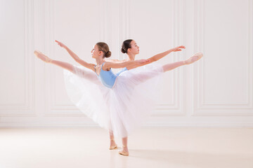 Obraz premium Young ballerinas having rehearsal at studio. Row of happy young ballerinas practicing at ballet barre, focus on first girl.