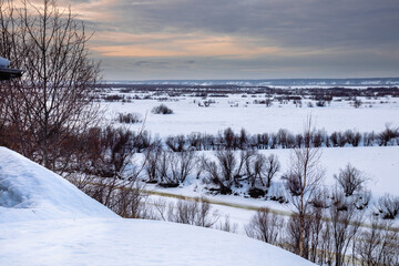View from the hill to a snow-covered river valley with tree lines.  Calm spinning rural landscape
