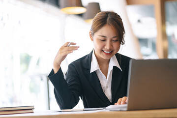 Smiling asian businesswoman sitting working on laptop in office.