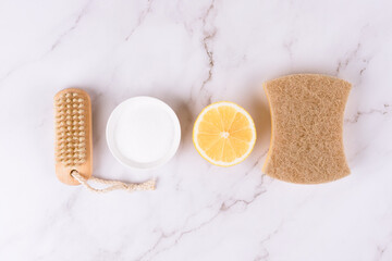 Natural household cleaners made of simple eco ingredients, bamboo brush, organic dishcloth, lemon, baking soda, citric acid on marble background with copy space. Green cleaning concept