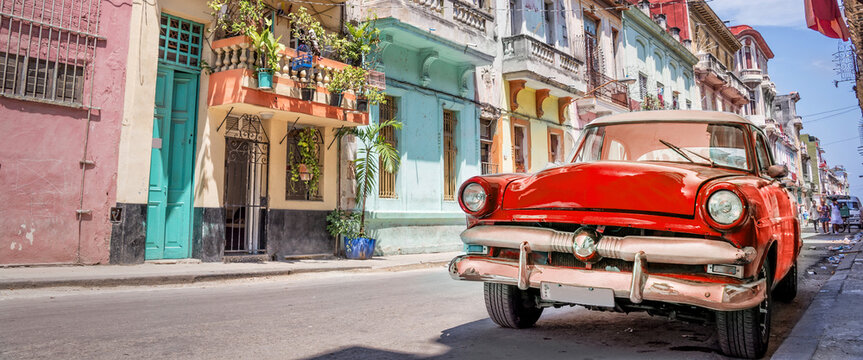 Vintage classic red american car in a colorful street of Havana, Cuba. Panoramic travel web banner.