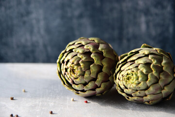 Fototapeta premium Still life with fresh artichoke flowers. Close up photo of beautiful natural pattern. Eating healthy concept. 