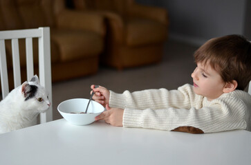 child eating breakfastwith cat