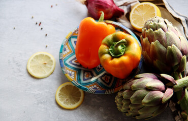 Top view photo of fresh seasonal vegetables on a table. Vibrant colors of bell pepper and two artichokes. Healthy eating concept. 
