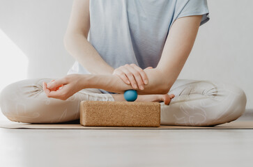 Obraz na płótnie Canvas Forearm muscles myofascial release with small therapy ball on cork block. Concept: self care practices at home, pain relief
