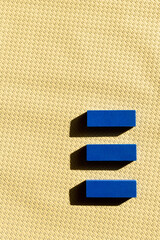 top view of three blue blocks on beige textured background.