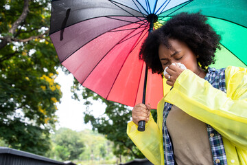 Front view portrait of an African American woman walking towards camera sneezing holding an...