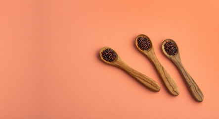 Organic brown grains of mustard in three wooden spoons