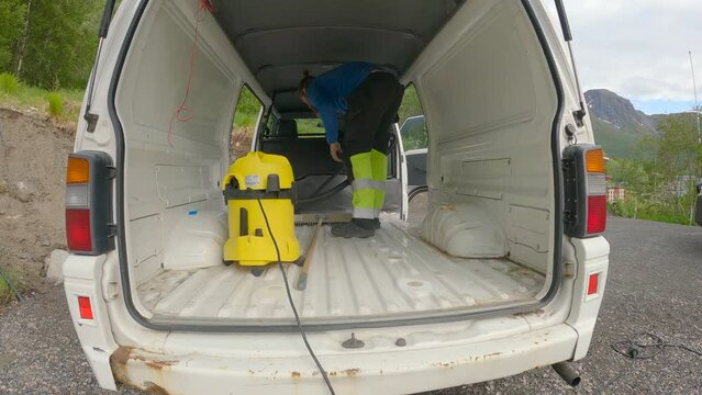 Man cleaning Camper Van with vacuum cleaner, preparing for coating, Van Build.