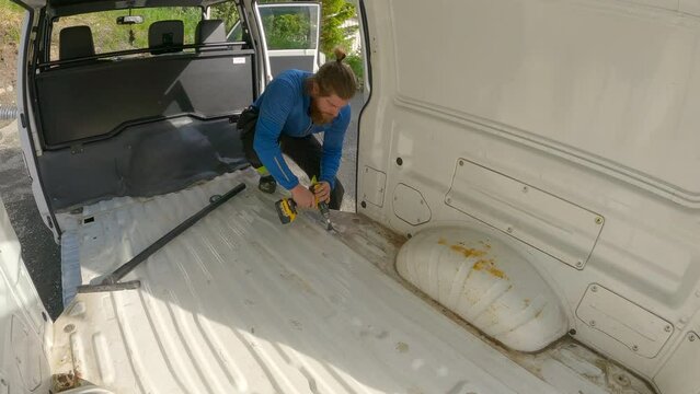 Young Man brushing inside of the Campervan for rust treatment. Veteran Camper Van Build.