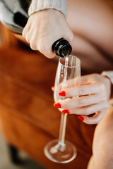 a woman pours champagne into a glass. sparkling wine for a party or hen party. the tradition of toasting and drinking alcohol on holidays.