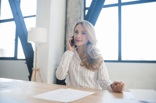 A blone businesswoman in her office talking on the phone