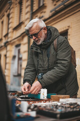 Garage sale, mature man buys antiques at the flea market. Elderly collector.