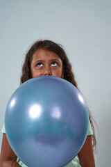 Thoughtful little girl hold balloon and look up