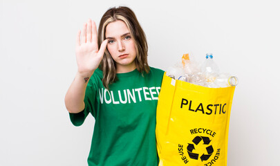 pretty caucasian woman looking serious showing open palm making stop gesture. ecology concept