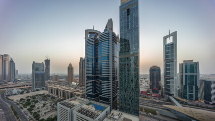 Aerial view of Dubai International Financial District with many skyscrapers day to night timelapse.