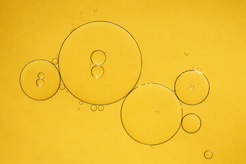 Golden yellow abstract oil bubbles or face serum background. Oil and water bubbles macro photography. - obrazy, fototapety, plakaty