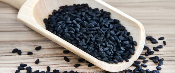 Fototapeta na wymiar Nigella black cumin seeds and spoon on wooden backround closeup