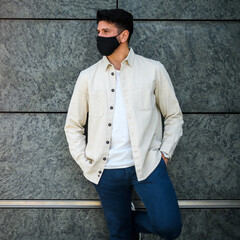 Obraz premium Young man with covid or coronavirus mask leaning against a wall