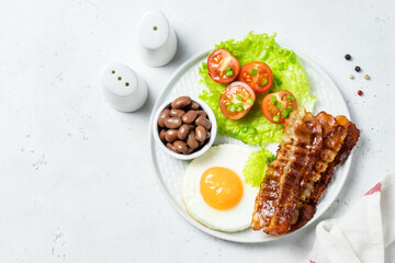 Egg and bacon, fresh tomatoes, beans, English breakfast on plate. Top view, copy space.