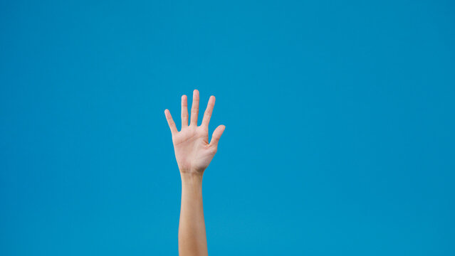 Young woman waving saying greeting, goodbye making hand gestures isolated over blue background. Copy space for place a text, message for advertisement. Advertising area, mock up promotional content.
