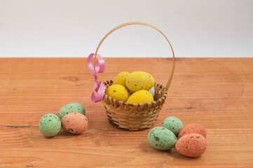 basket with easter chocolate eggs wrapped in colored paper on wood