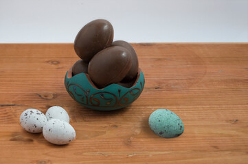 small bowl with chocolate easter eggs wrapped in colored paper on wood