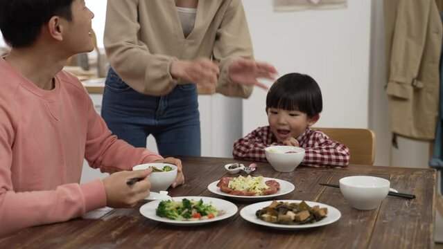 slow motion of lovely hungry Asian preschool boy saying wow as his mom is serving a plate of meat for family of three on dining table at home