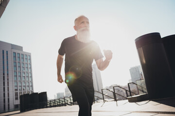 Photo of sportive strong man pensioner dressed black clothes running fast enjoying morning exercise...