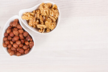 Hazelnuts and walnuts in white bowl, healthy nutrition and lifestyle concept, place for text