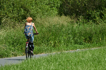 Frau mit dem Fahrrad unterwegs im Sommer auf dem Lahn-Radweg