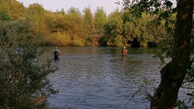 Two anglers inside the river fishing