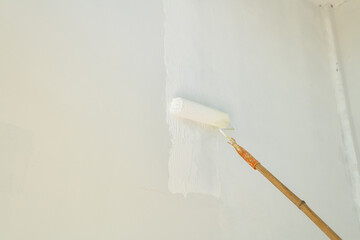 Painting of walls in a white color by the roller brush.