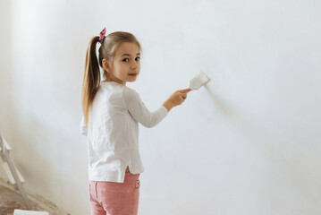 little blonde girl with wall paint roller during home renovation