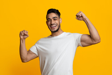 Fototapeta premium Cheerful athletic middle eastern man showing his muscles
