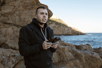 Young man operating a drone over the sea
