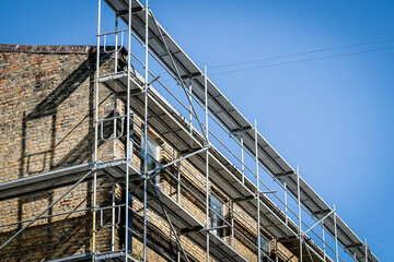 Reconstruction of an old brick house. Scaffolding for construction, construction site. Selective focus