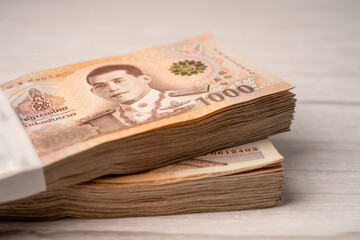 Stack of Thai baht banknotes on wooden background, business saving finance investment concept.