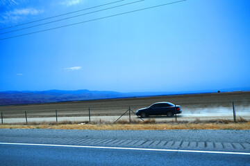 Fototapeta premium Lines separating mountains, hills, dried grass, farm land, and orchards beside highway 99 with wire fence under the blue sky