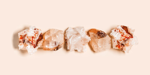 White beige quartz crystals on pale pink color background with copy space,  top view natural gemstone. Quartz mineral stone healing crystal, precious gem, flat lay, alternative medicine