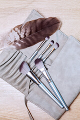A set of makeup brushes of various shapes lies on the makeup artist's table with a cover of their...