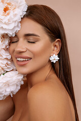 Pretty woman with bright makeup. Beautiful white girl with flowers. Stunning brunette girl with bouquet of peonies. Closeup face of young beautiful woman with a healthy clean skin and beautiful smile.