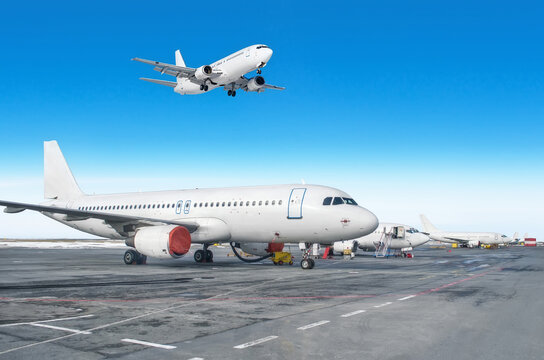 Passenger aircraft row, airplane parked on service before departure at the airport. One landing to runway in the blue sky.