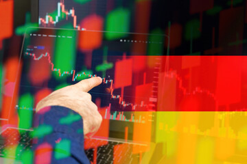 Germany downtrend of the economy in a world crisis. Man hand shows on the decreasing candle stick graph chart in the stock market with the flag on the background, March 2022, San Francisco, USA