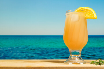 Drinking glass of orange lemonade. Refreshing summer fruit cocktail at beach bar