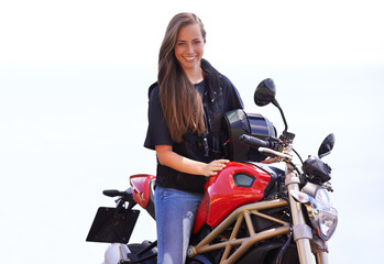 Fototapeta na wymiar Shes a true biker chick. A beautiful young woman sitting on her red motorcycle.