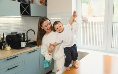 Happy mom and cheerful baby in the kitchen. Mother's love. Motherhood. The child is restless.