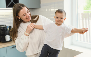 Happy mom and cheerful baby in the kitchen. Mother's love. Motherhood. The child is restless.
