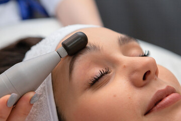 Naklejka premium A girl's face in close-up during a facial treatment at a cosmetologist.The cosmetologist does biomechanical stimulation of the face to the client.Care and rejuvenation procedure